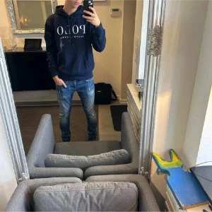 Mörkblå hoodie från Ralph Lauren - Säljer en snygg mörkblå hoodie från Ralph Lauren med stor POLO-logga på bröstet. Tröjan har en klassisk design med huva och dragsko samt långa ärmar. Perfekt för en avslappnad stil.