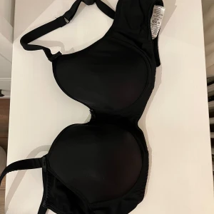 Svart BH från Trofé - Säljer en svart BH från Trofé i storlek 75C. Den har justerbara axelband och en slät design som ger ett stilrent intryck. Perfekt för vardagsbruk.