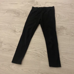 Svarta leggings från Spooky Night - Säljer ett par svarta leggings från Spooky Night i storlek EU 122. Perfekta för en bekväm och stilren look. De har en elastisk midja för extra komfort.