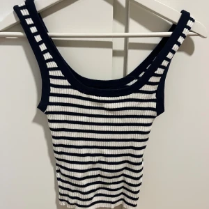 Randig ribbad linnetopp - Snygg randig linnetopp i blå och vit med ribbad struktur. Perfekt för sommardagar med sin ärmlösa design och bekväma passform.