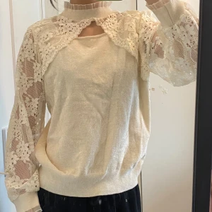 Beige tröja med spetsdetaljer - Säljer en elegant beige tröja med vackra spetsdetaljer på ärmarna och axlarna. Aldrig använd. 