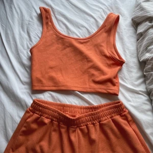 Sommar set - Säljer en snygg orange ribbad linnetopp. Toppen är ärmlös och croppad, perfekt för varma dagar. Den har en enkel och stilren design som passar till mycket.
