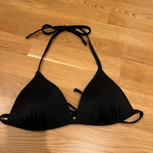 Svart bikiniöverdel - Snygg, svart bikiniöverdel med knytband i nacken och ryggen. Sällan använd eftersom den är för stor för mig och därav mycket bra skick! Den är från Bik Bok i storlek M. Bra stöd (vadderad). Skriv gärna om du har några frågor🤗