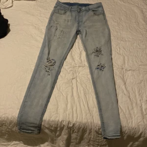 Ljusa slitna jeans - Snygga ljusa jeans med slitningar på framsidan. De har en klassisk femficksdesign och en smal passform. Perfekta för en avslappnad stil.