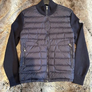 Moncler Cardigan - Snygg mörkblå cardigan från Moncler med dragkedja. Jackan har långa ärmar och två praktiska fickor med dragkedja framtill. Fungerande qr kod och nft tag (skanbar logga). Perfekt för kyligare dagar. 1️⃣; 1️⃣För mer info är det bara att ta och skriva. Priset kan diskuteras vid snabba affärer.