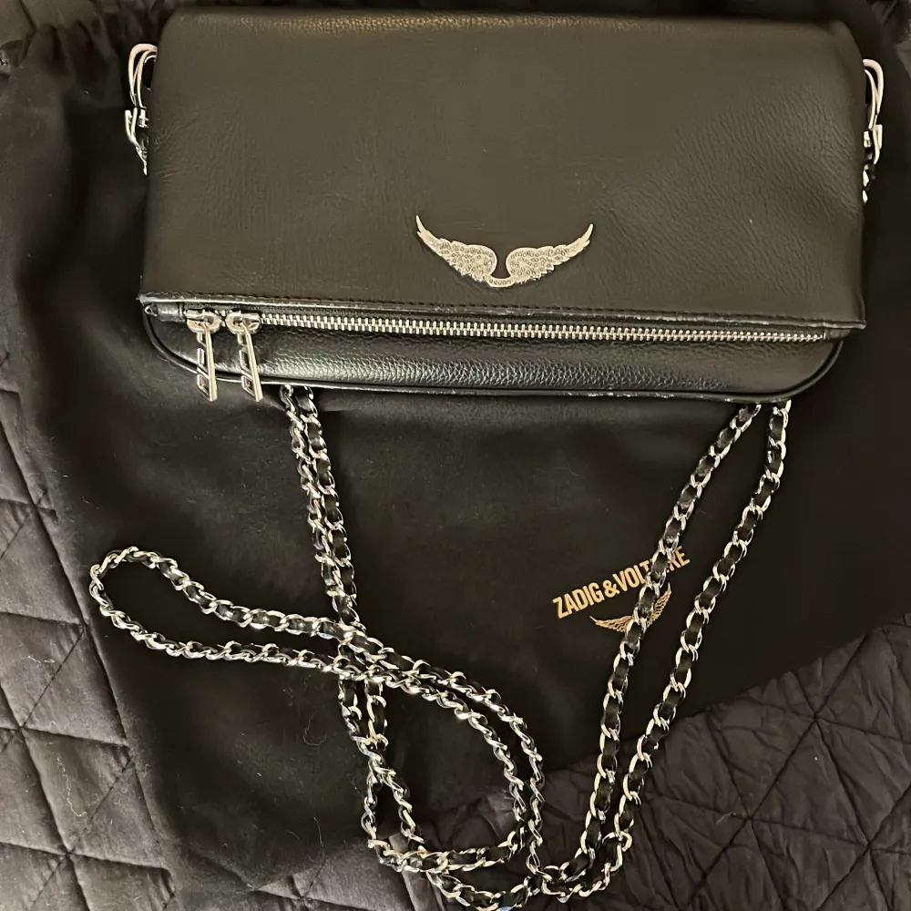 Hej, intresse koll på min Zadig & Voltaire väska i skinn, med silverdetaljer och kedjerem. Väskan är i fint skick, men har små defekter längst ner på kanten, som knappt syns. Den är inköpt 2022 men är väl omhändertagen. Den kommer tyvärr inte till användning längre. Pris är inte hugget i sten, går att diskutera! Bara att höra av sig vid frågor eller fler bilder! 🥰 . Laukut & Käsilaukut.