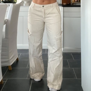 Beige cargobyxor  - Beige cargobyxor i jeans med fickor och en avslappnad baggy passform. Perfekta för en casual look. Byxorna har en knapp och dragkedja framtill. Midrise. Midja 37 cm. Innerben 77 cm. Strl 38 men små i strl. Min vanliga strl är S 34/36.