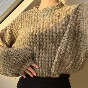 Beige stickad tröja - Mysig beige stickad tröja med ribbad struktur. Perfekt för kyliga dagar med sin avslappnade passform och långa ärmar. En stilren och bekväm tröja som passar till många tillfällen.