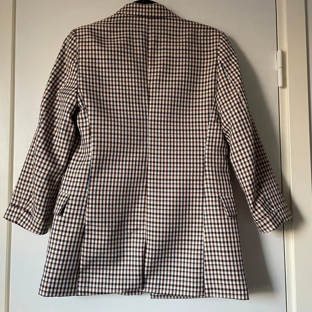 Snygg rutig kavaj från Stradivarius i beige, blå och brun. Kavajen har en klassisk design med dubbelknäppning och långa ärmar. Perfekt för en stilren look.. Takit.