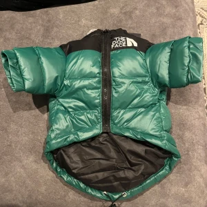 Grön pufferjacka för hundar från The Dog Face - Säljer en grön pufferjacka för hundar från The Dog Face. Jackan har en dragkedja framtill och är kortärmad med svart detaljerad axelparti. Den  har en justerbar snörning i nederkanten för bättre passform. Är storlek xl men skulle säga att den passar s. Kan mäta om så önskas🙂