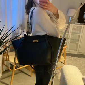 Svart axelväska från Gina Tricot - Svart axelväska från Gina Tricot i skinnimitation. Axelbanden är något slitna, därav priset. Utöver det i väldigt gott skick 🥰