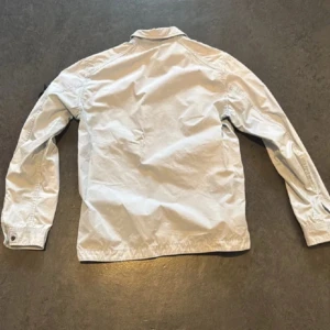 Vit jacka från Stone Island - Säljer nu en ljusblå overshirt från Stone Island. 100% äkta ni kan själva kolla upp det igenom koden på bild 3. Inga defekter alls. Storlek M