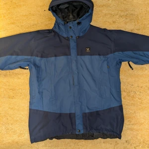 Haglöfs jacka storlek L fräsch & billig! - Säljer en blå jacka från Haglöfs i storlek L med en luva man kan vika in. Jackan har en stilren design med mörkare blå detaljer och praktiska fickor med dragkedjor. Möts upp i centrala Göteborg eller så kan jag skicka via post om det önskas!                   Pris kan diskuteras vid snabb affär!!!