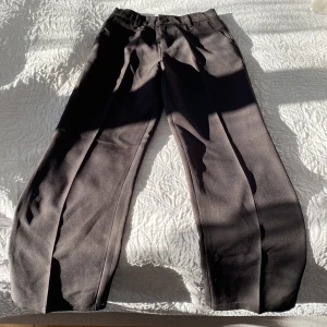 Svarta kostymbyxor från Lindex  - Snygga svart kostymbyxor från Lindex med hög midja och raka ben. Byxorna har en knapp och dragkedja framtill samt hällor för bälte. Perfekta för en stilren look. Har ändast använts 1 gång men har blivit för små.