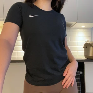 Svart t-shirt från Nike - Svart t-shirt från Nike med korta ärmar och klassisk passform. Vit Nike-logga på bröstet. Storlek M men skulle säga mer en S.