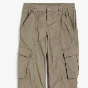 Beige cargopants med fickor - Snygga beige cargopants med praktiska fickor på sidorna. Byxorna har en elastisk midja för extra komfort och en klassisk cargostil. Perfekta för en avslappnad look.