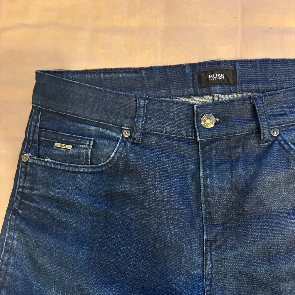 Snygga blå jeans från Boss med stretchmaterial för extra komfort. Klassisk femficksdesign med knapp och dragkedja framtill. Perfekta för en stilren look.. Farkut & Housut.