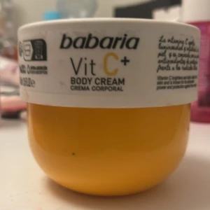 Babaria Vit C+ Body Cream - Babaria Vit C+ Body Cream i en rund, gul burk med vit lock. Denna kroppskräm är berikad med vitamin C för att ge huden en fräsch och strålande känsla. Perfekt för daglig användning för att återfukta och vårda huden. Använd är den 2-3 gånger 