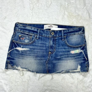 Lågmidjad jeanskjol med hål Hollister  - Hollister kjol. Ny med lapp. W26 något stor i storleken. Midjemått:39 total längd:25. Köp sker via köp nu, jag postar inom 24h. Kvar tills markerad såld 