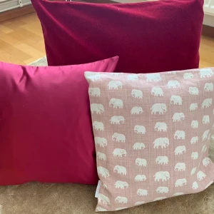 Rosa kudde med elefantmönster svenskt tenn  - Charmig kudde i ljusrosa med ett sött elefantmönster i vitt. Perfekt för att ge ditt rum en lekfull och mysig känsla. Kudden har en fyrkantig form och är mjuk och bekväm att luta sig mot.