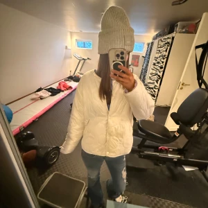 Vit quiltad dunjacka - Säljer en mysig vit quiltad dunjacka med dragkedja. Perfekt för kyliga dagar. Jackan har en normal passform och långa ärmar. En stilren och praktisk jacka för vintern.