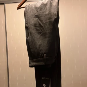 Grå kostymbyxor från Elvine - Oanvända (med prislappen kvar) grå kostymbyxor från Elvine med en klassisk design. Byxorna har en rak passform och är tillverkade i ett stilrent material. De har hällor för bälte och knäppning fram. Perfekta för en stilren look. Nypris 1200kr. Vid frågor är det bara att skriva 