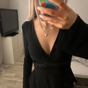 Svart tröja från Gina Tricot - Snygg svart tröja från Gina Tricot i storlek XS. har en v-ringad design med spetsdetaljer i midjan och långa ärmar. Perfekt för en stilren look.