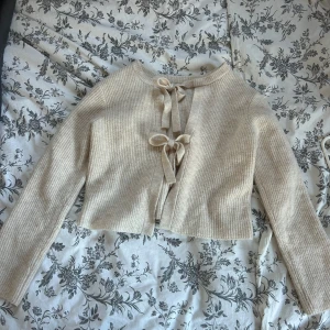 Vit/beige stickad kofta från Object - Säljer en vit/beige stickad kofta från Object, med en söt knytning framtill  som man även kan ha vid ryggen om man föredrar det🥰