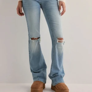 Ljusblå bootcut jeans - Snygga ljusblå bootcut jeans med slitningar på knäna. De har en klassisk femficksdesign med knappar på bakfickorna. Perfekta för en avslappnad stil. Använda ett fåtal gånger endast💋