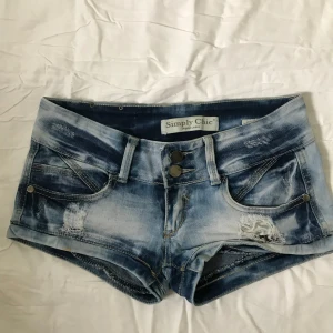 Lågmidjade jeansshorts med slitningar - Säljer dessa otroligt snygga jeansshorts från Simply Chic, midjemåttet är 35cm. Tveka inte vid frågor!🤪💕