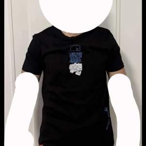 Svart t-shirt med tryck - Snygg svart t-shirt från Off-White med unikt tryck i blått och vitt på både fram- och baksidan. T-shirten har korta ärmar och en normal passform. Perfekt för en trendig look.