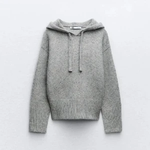 Grå stickad hoodie från Zara - Mysig grå stickad hoodie från Zara med ribbade muddar och dragsko i huvan. Perfekt för kyliga dagar och ger en avslappnad stil. Passar bra till jeans eller leggings.