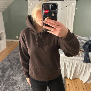 Brun hoodie från Bik Bok - Säljer en brun hoodie från Bik Bok i storlek S. Den har en klassisk design med en stor ficka framtill och justerbar huva med dragsko. Perfekt för en avslappnad stil.