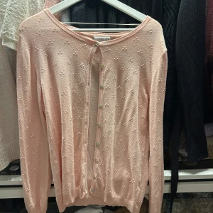 Rosa kofta från Fransa - Säljer en söt rosa kofta från Fransa med små pärldetaljer över hela ytan. Koftan har långa ärmar och knäpps med knappar framtill. Perfekt för en stilren och feminin look. 🌸