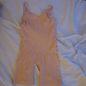 Beige bodysuit - Säljer en beige bodysuit med smala axelband. Tillverkad i ett stretchigt material av polyamid och elastan. Perfekt för en bekväm och stilren look. Ger en extra liten snatch i midjan.