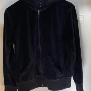 Svart velour hoodie från b.young L - Säljer en svart velour hoodie med dragkedja och huva. Den har långa ärmar och en bekväm passform. Perfekt för en avslappnad stil. Inget snöre medföljer. Munkjacka! 