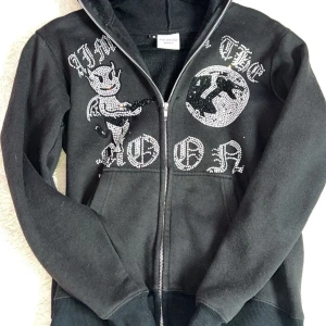  Aim for the moon zip up - Snygg svart hoodie med dragkedja och coola strassdetaljer som bildar ett djävulsmotiv och texten 'Aim for the Moon'. Perfekt för att sticka ut med en unik stil. Hoodien har långa ärmar och en bekväm passform. ❗️lite nopprig❗️