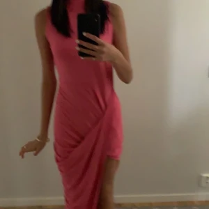 Rosa klänning med slits - Jättefin klänning från ClubL. Har en slits, jätte fint skick! Storlek 10 vilket motsvarar ungefär xs/s. Kontakta om ni vill ha tydligare bild på där man ser hela bilden.