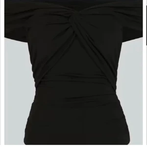 Svart offshoulder topp - Snygg svart offshoulder topp med knytdetalj framtill. Toppen har en tight passform och är perfekt för en stilren look. Materialet är mjukt och stretchigt för extra komfort. Säljer då den inte kommer till användning💕💕