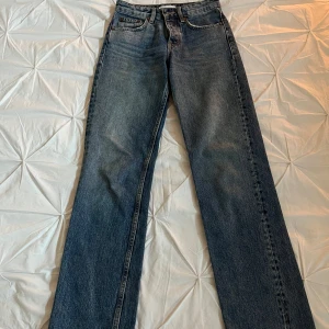 Blå jeans med rak passform - Snygga blå jeans med rak passform och klassisk design. De har en knapp och dragkedja framtill samt fem fickor. Perfekta för en avslappnad stil. Samt en slits längst ner på jeansen 