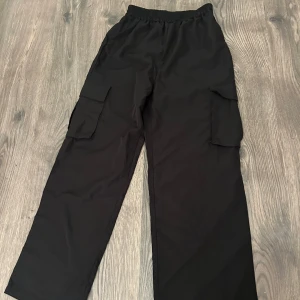 Svarta cargopants med fickor - Snygga svarta cargopants med praktiska fickor på sidorna. Byxorna har en loose passform och elastisk midja för extra komfort. Perfekta för en avslappnad stil.