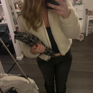 Vit teddyjacka från H&M - Mysig vit teddyjacka från H&M med dragkedja framtill. Perfekt för kyliga dagar med sin fluffiga och varma design. Jackan har en klassisk krage och långa ärmar.