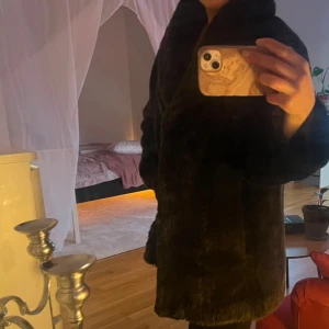 Mörkbrun  pälsjacka - Säljer en elegant svart pälsjacka med en lyxig känsla. Jackan har en klassisk design med långa ärmar och en mjuk, varm textur. Perfekt för kyliga dagar när du vill känna dig extra stilren. Passar M 