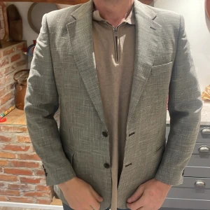 Grå rutig kavaj - Snygg grå rutig kavaj med klassisk passform. Kavajen har två knappar framtill och är perfekt för både formella och semi-formella tillfällen. Den har en tidlös design som passar bra till olika outfits.