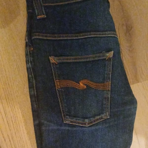 Mörkblå jeans med orange sömmar - Säljer dessa feta jeans från nude-jeans bara används nåra gånger bra skick. Riktigt sköna. Är hål i skrevet som lagats av nudie jeans syns inte när man använder dom