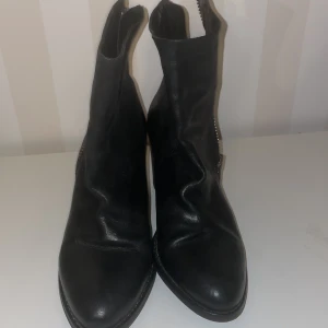 Svarta boots med dragkedja Billi Bi - Snygga svarta boots i skinn från Billi Bi Copenhagen i nyskick med dragkedja på sidan. De har en klack och en spetsig tå, vilket ger dem en stilren look. Perfekta för både vardag och mer uppklädda tillfällen.