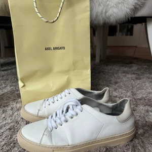 Vita sneakers från Axel Arigato (strlk 43) - Stilrena och sparsamt använda vita sneakers med beig underdel från Axel Arigato.  