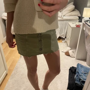 Olivgrön kortkjol med knappar - Trendig olivgrön kortkjol med knappar framtill, är lite ojämt klippt men är ej så synligt och går att klippas till💚💚💚