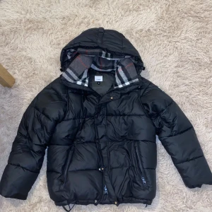Svart dunjacka från Burberry - Svart jacka från Burburry, helt ny och inga skador. Man kan ta bort armarna så att jackan blir till en väst. Riktigt varm jackan för vintern. FAST PRIS!