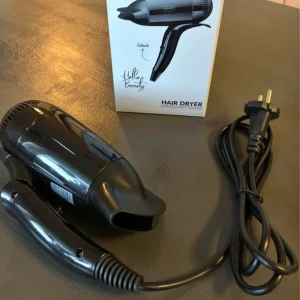 Liten svart hårfön från Havsö! - Liten svart hårfön som kan fällas ihop. Perfekt för resan eller för dig som vill spara plats. Två värmelägen och överhettningsskydd. Kabellängd 1,8 m. 